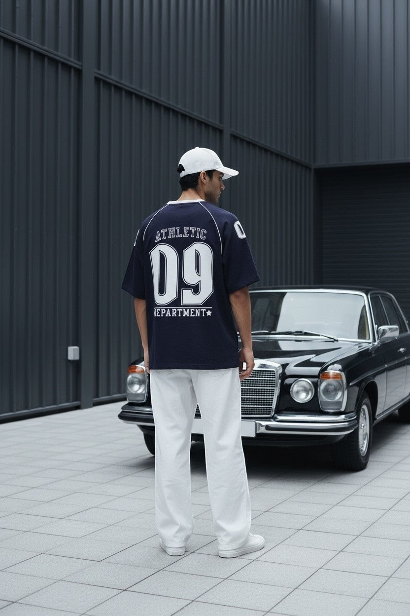 Koti Apparels navy blue cotton graphic t-shirt with white piping on raglan sleeves and "Athletic Department 09" graphic on back.