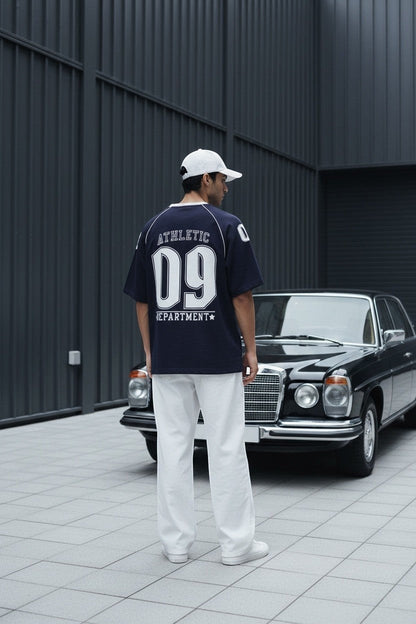 Koti Apparels navy blue cotton graphic t-shirt with white piping on raglan sleeves and "Athletic Department 09" graphic on back.