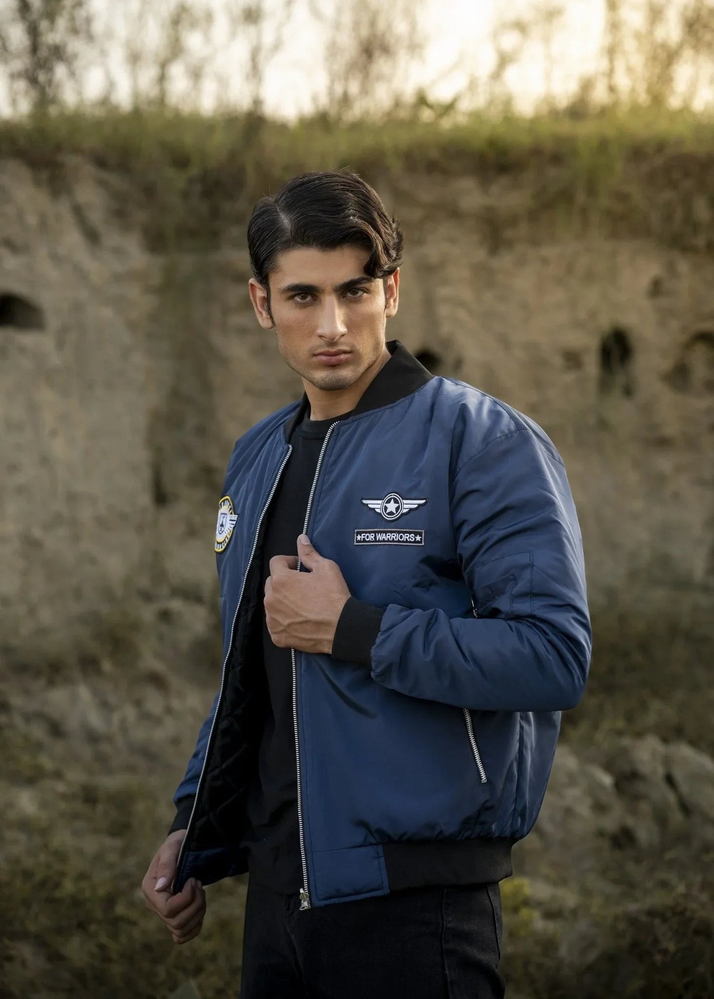 Koti Apparels navy blue reversible bomber jacket with embroidered patches, worn by a male model outdoors.