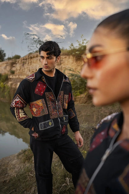 Koti Apparels black canvas jacket with multicolour patchwork panels, long sleeves, zipper, and pockets. Model stands outdoors.