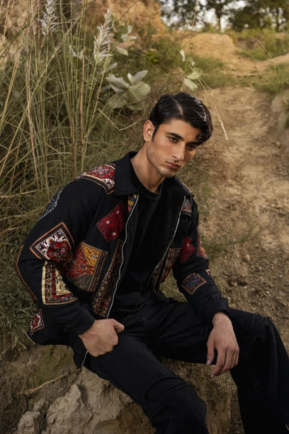 Koti Apparels black canvas jacket with multicolour patchwork panels on sleeves and collar, featuring a zipper closure and front pocket.
