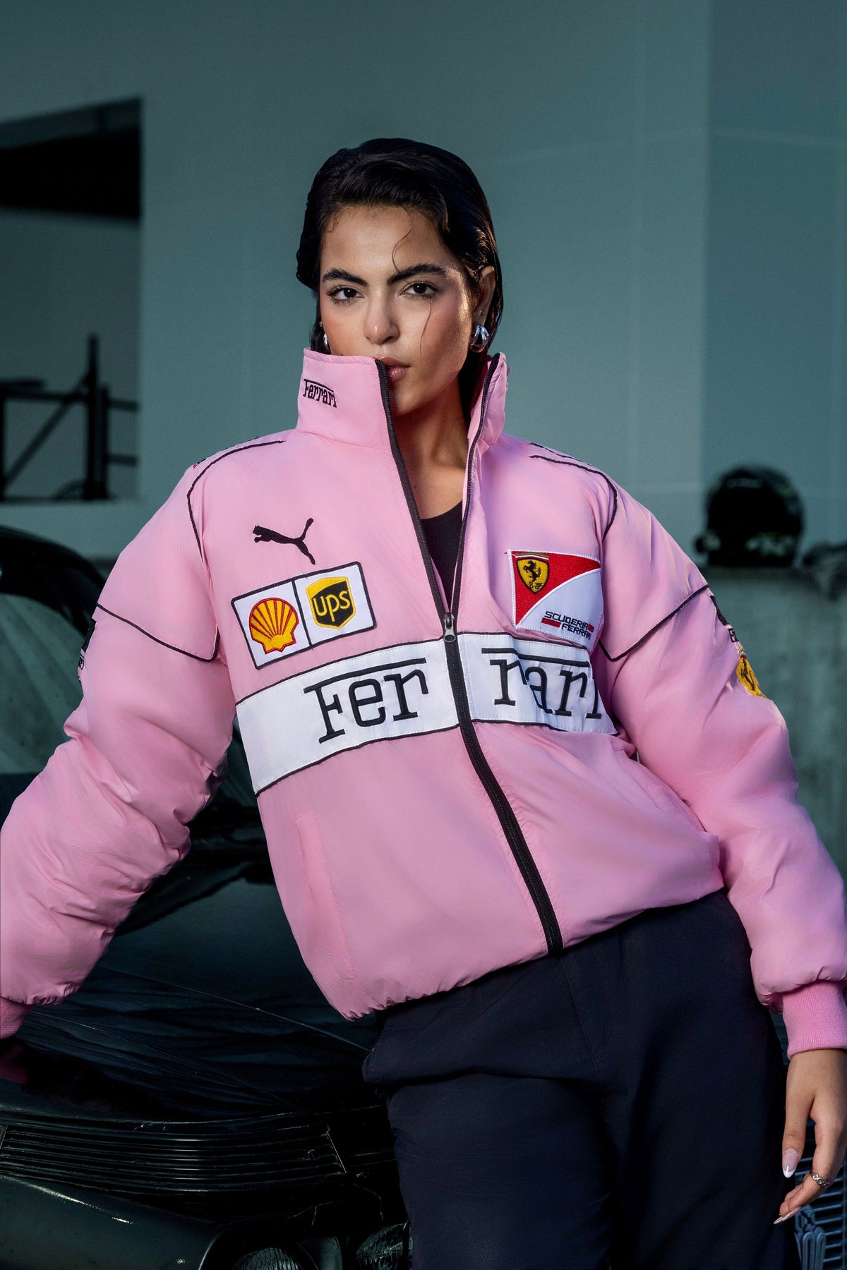 Model wearing a pink Koti Apparels Ferrari racing jacket with embroidered sponsor logos and a high collar