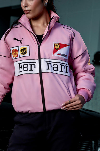 Model wearing a vibrant pink Koti Apparels Ferrari racing jacket with embroidered F1 sponsor logos and a zip front.