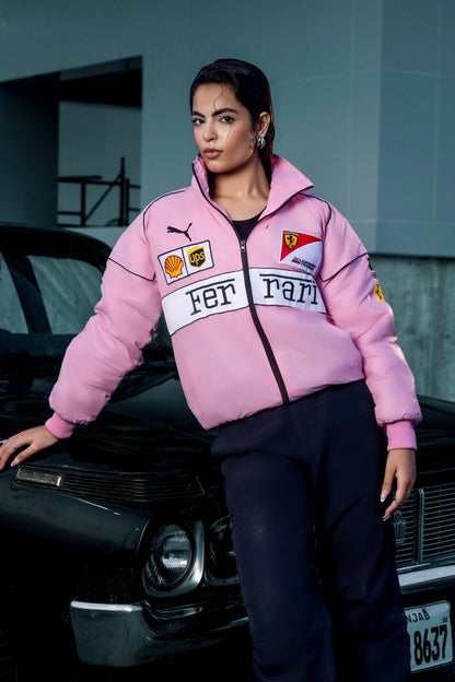 Koti Apparels pink Ferrari racing jacket with embroidered logos worn by a woman leaning against a black car