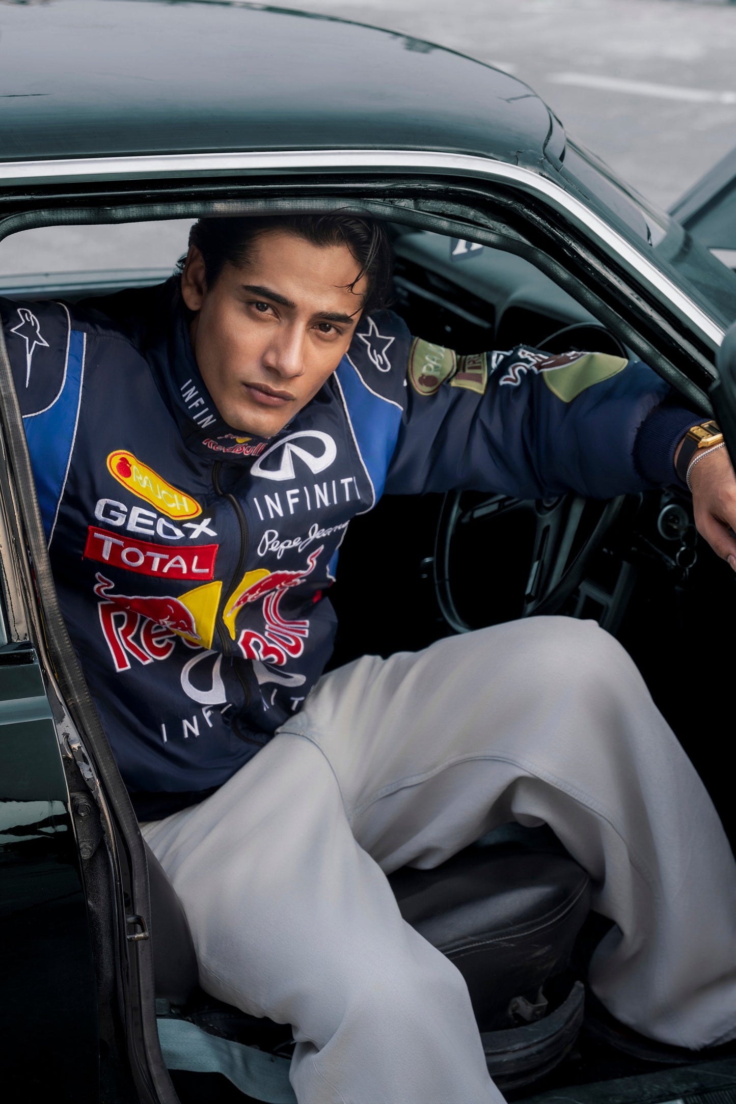 Koti Apparels Red Bull racing jacket with embroidered team logos worn by a man sitting in a vintage car