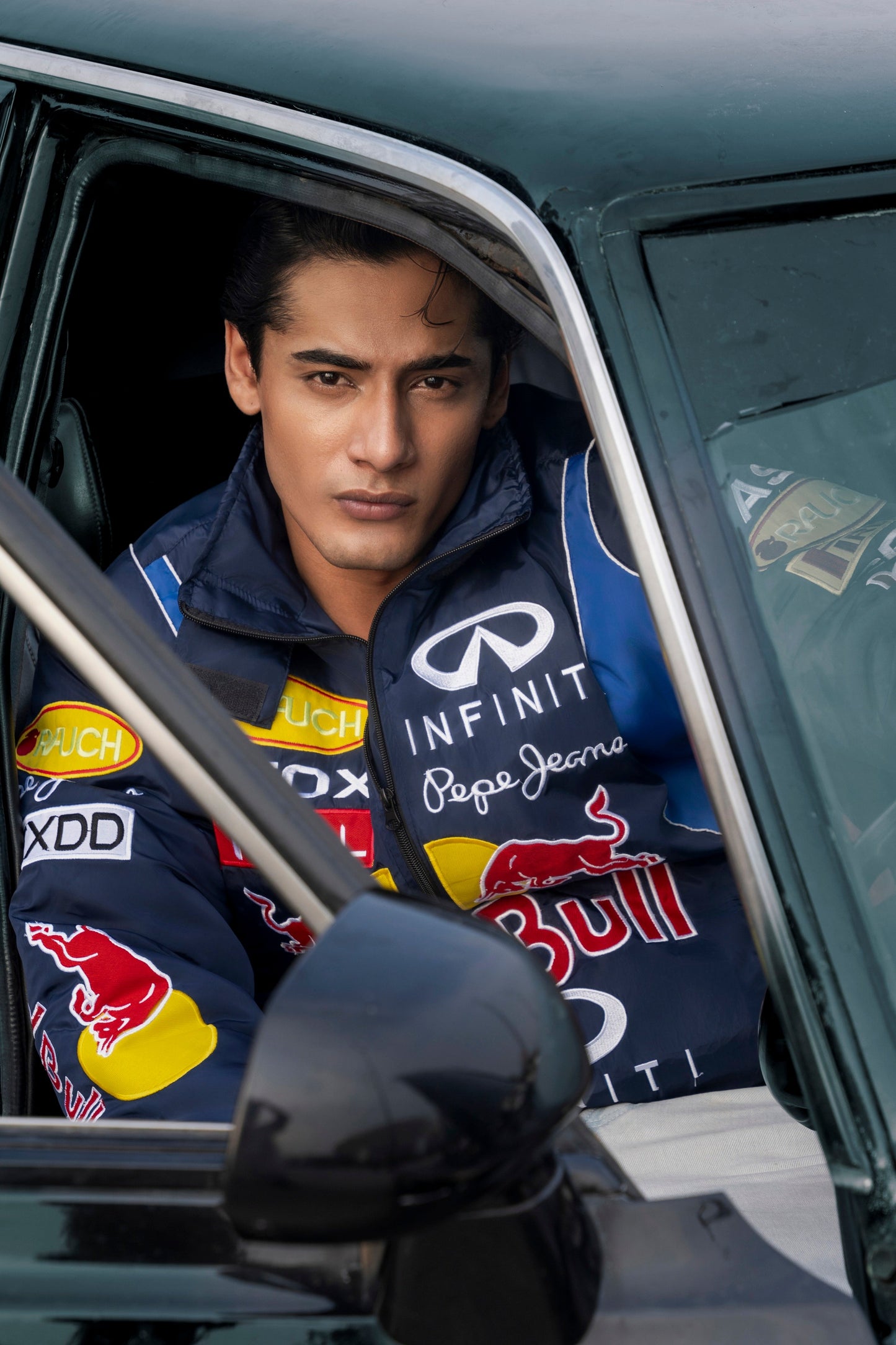 Koti Apparels Red Bull racing jacket with embroidered logos worn by a man sitting in a car