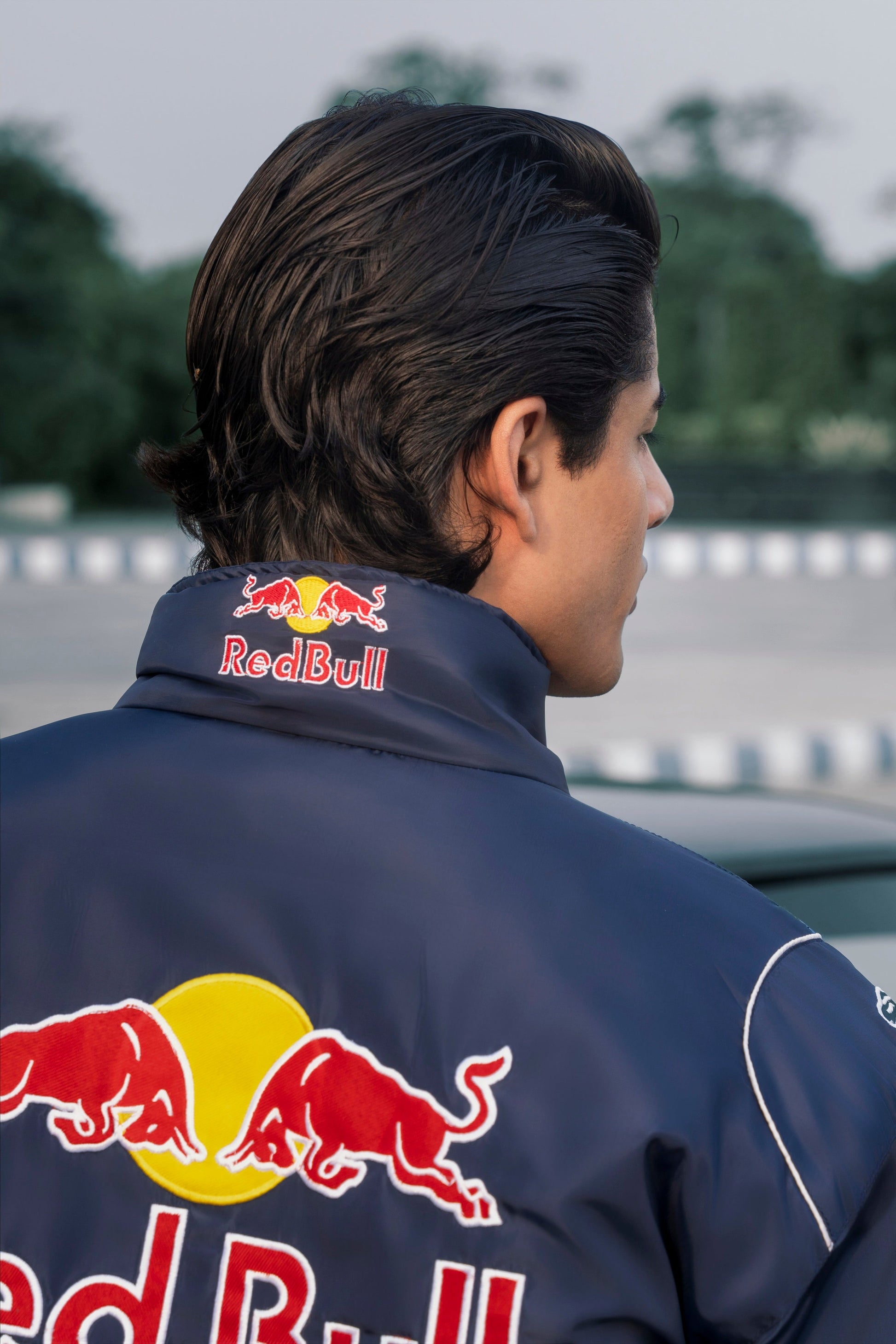 Koti Apparels navy blue Red Bull racing jacket with detailed embroidered logos worn by a man outdoors
