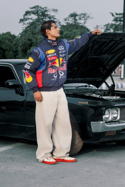Koti Apparels Red Bull racing jacket with embroidered logos worn by a man standing next to a black car