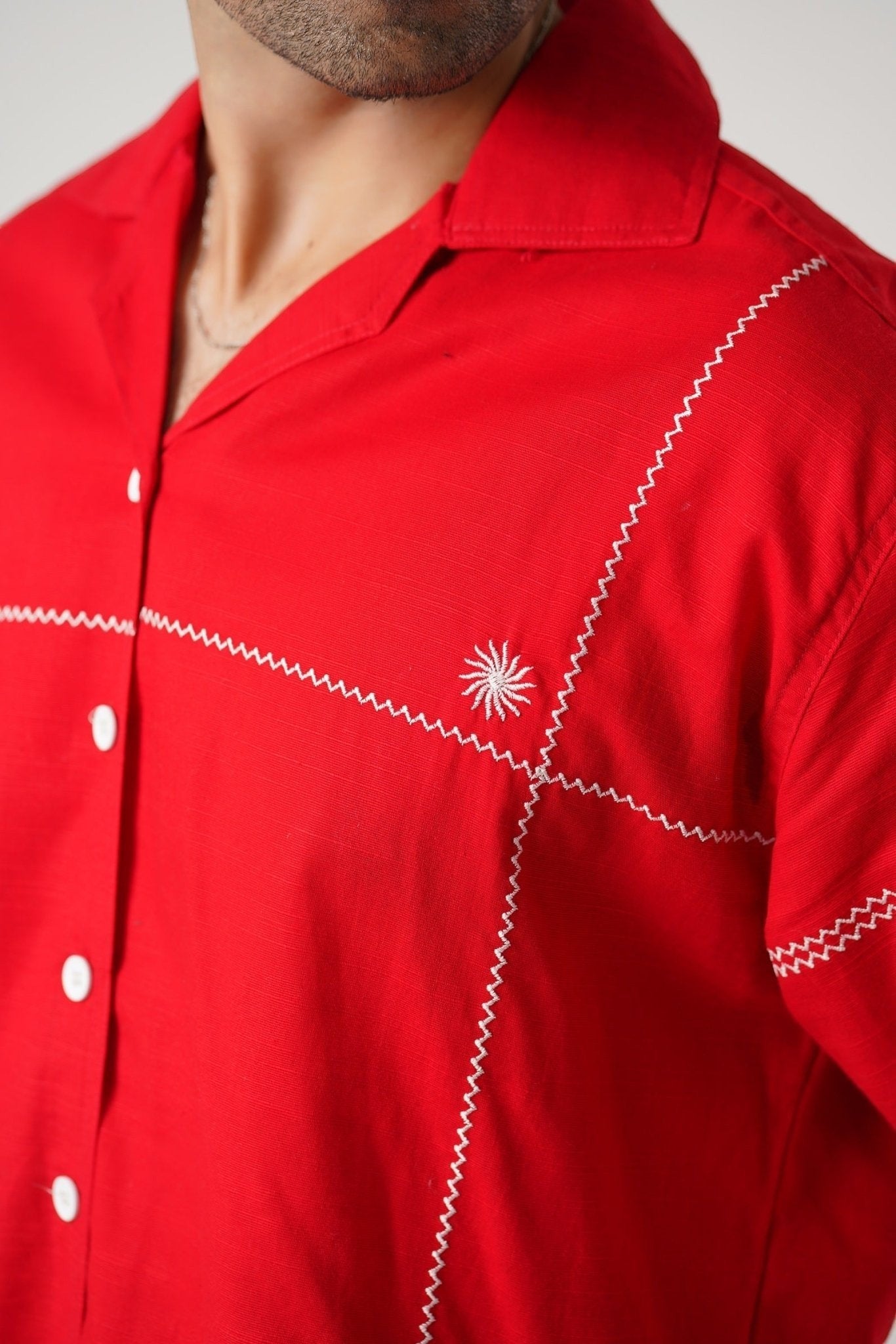 Koti Apparels red unisex shirt with white zig-zag embroidery and starburst motif. Full sleeves, button-down front, open collar.