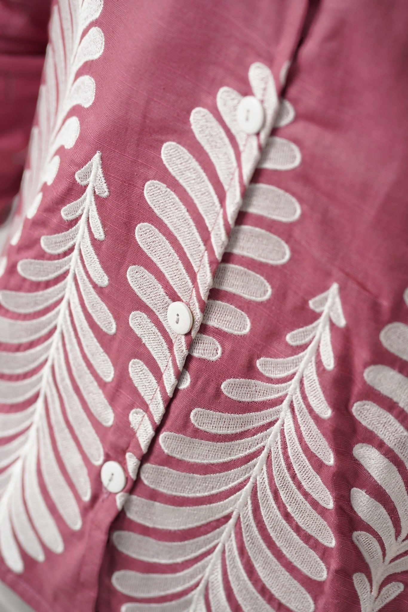 Koti Apparels rose pink unisex shirt with white leaf embroidery on the hem and button-down front.
