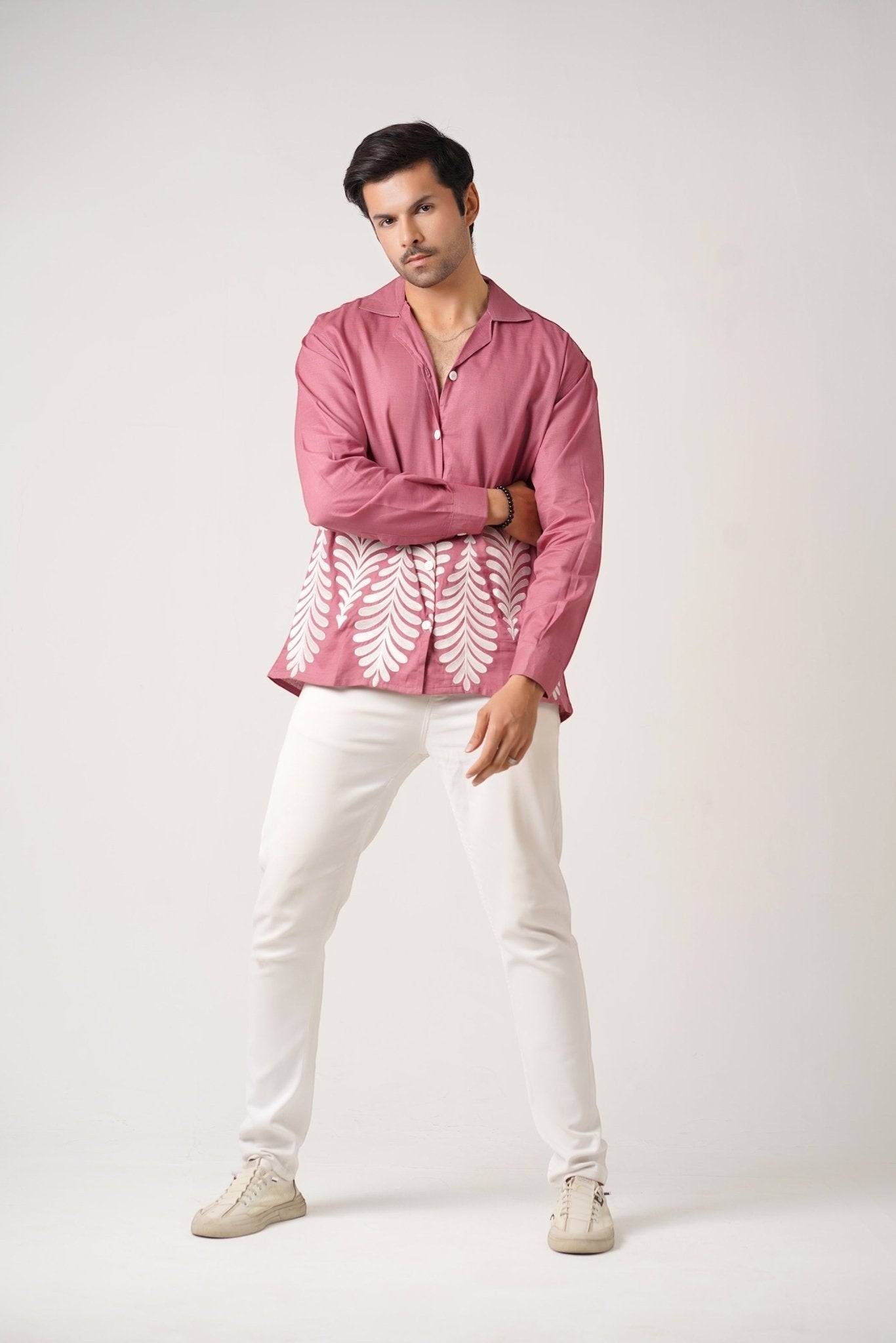 Koti Apparels rose pink unisex shirt with full sleeves, spread collar, and leaf embroidery on the hem. Model wears white pants.