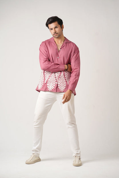 Koti Apparels rose pink unisex shirt with full sleeves, spread collar, and leaf embroidery on the hem. Model wears white pants.