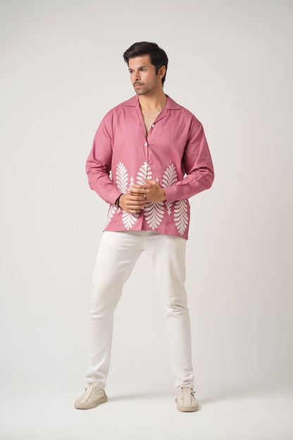 Koti Apparels rose pink unisex shirt with full sleeves, spread collar, and white leaf embroidery on the hem. Model wears white pants.