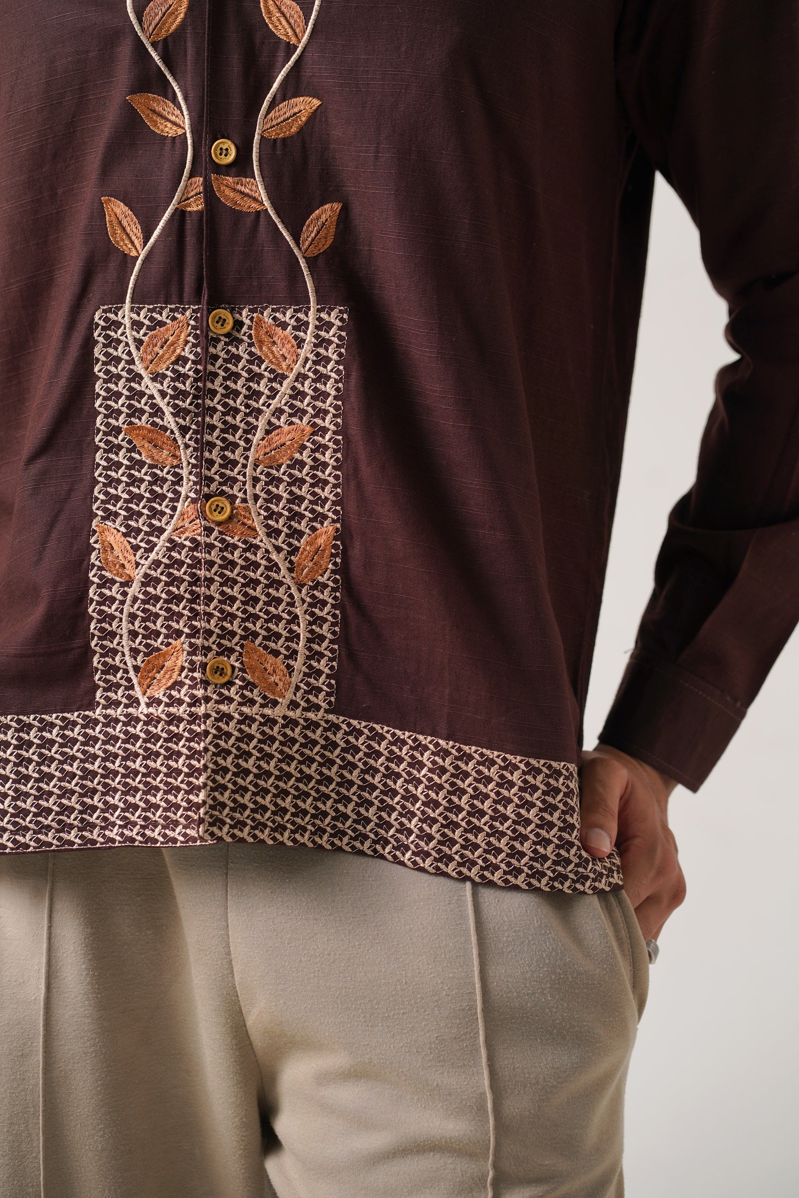 Brown long-sleeve top with leaf pattern and beige pants on a plain background