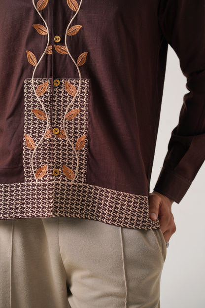 Brown long-sleeve top with leaf pattern and beige pants on a plain background