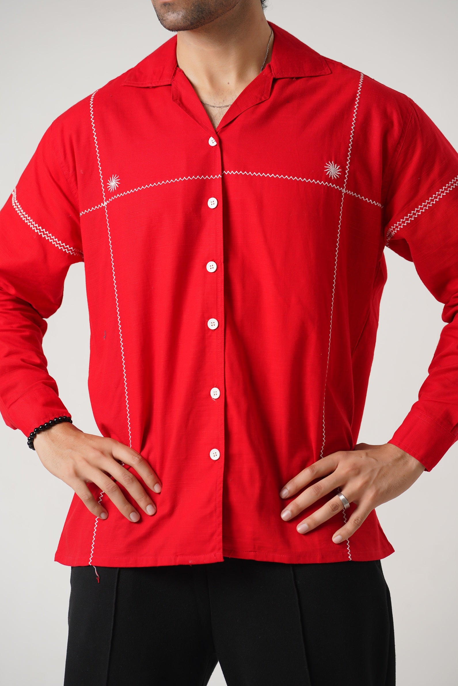 Red shirt with white stitching worn by a person on a plain background